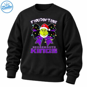 Grumpy green Christmas character in a Santa hat with a purple bow, colorful holiday lights, and Sacramento Kings lettering