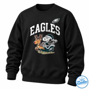Snoopy in a teal winter outfit rides a sleigh with a red-nosed reindeer beneath bold white EAGLES lettering and an eagle emblem.