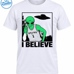 Green alien in a gray SPURS number 1 basketball jersey pointing upward beneath a UFO with bold I BELIEVE text