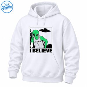 Green alien in a gray SPURS number 1 basketball jersey pointing upward beneath a UFO with bold I BELIEVE text